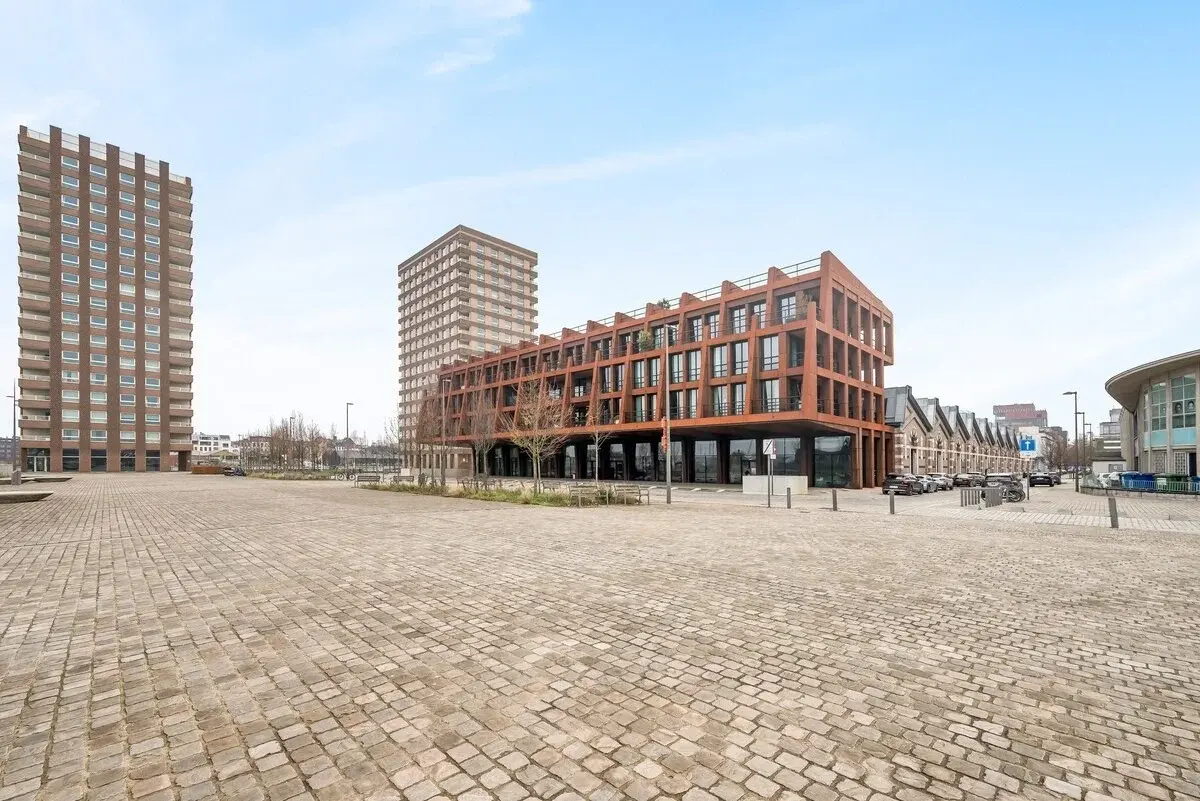 Immeuble moderne à façade en acier rouillé sur une place pavée à Anvers