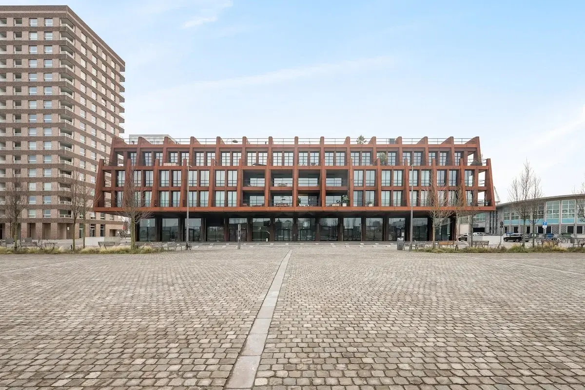 Modernes Apartmenthaus mit rostfarbener Stahlfassade an einem gepflasterten Platz in Antwerpen